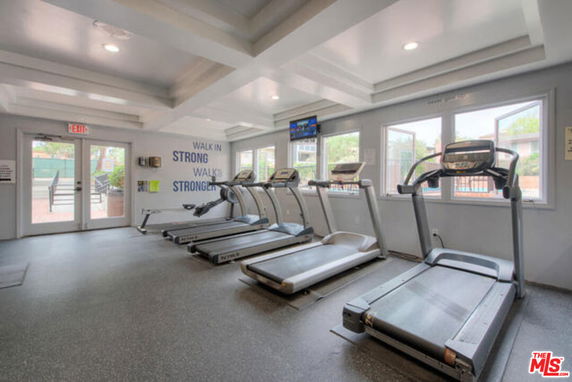 Indoor gym area with treadmills and large windows.