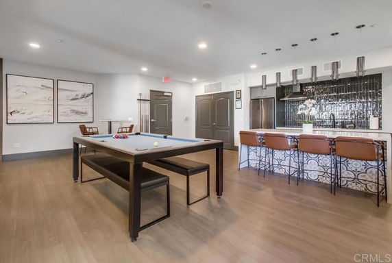 Interior of a recreation area with a pool table and bar seating.