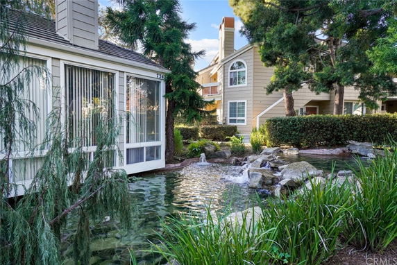 Front view of a multi-story house with large windows and adjacent pond.