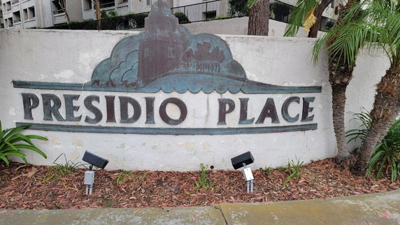 Sign for Presidio Place with palm trees and landscaping in the background.