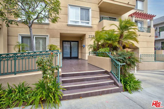 Front view of a multi-story residential building entrance with stairs and railings.