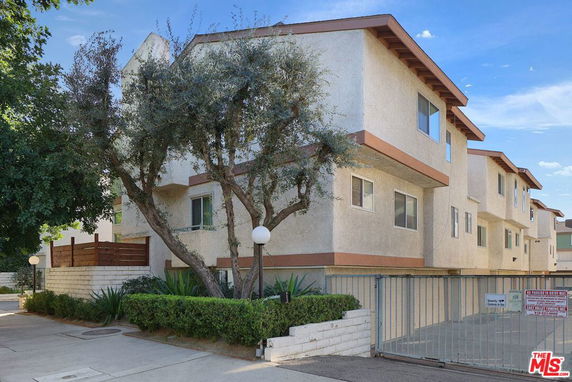Side view of a multi-story apartment building with a gated entrance.