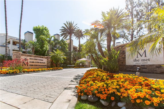 Front view of a multi-story residential building with palm trees and landscaped entrance.