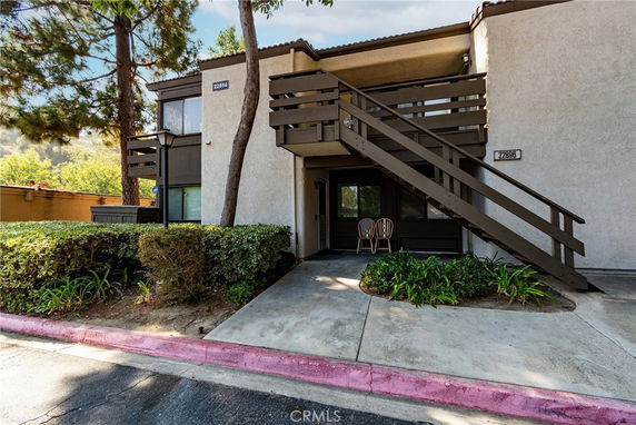 Front view of a two-story apartment building with exterior stairs and a small patio.