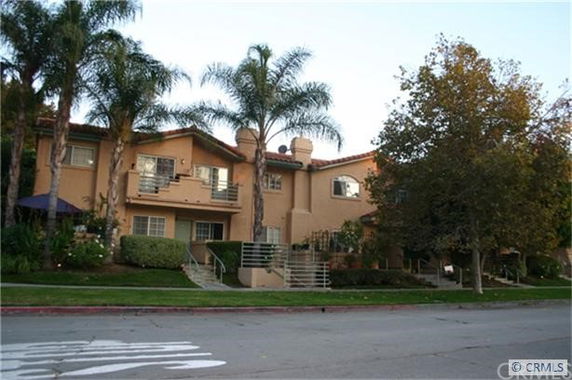 Front view of a multi-story residential building with balconies and a stairway entrance.