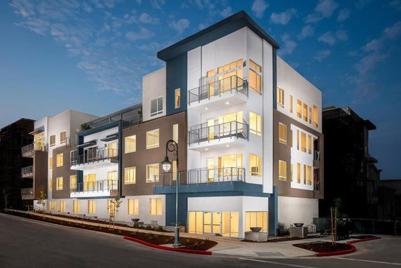 Front view of a modern multi-story residential building with balconies and large windows.