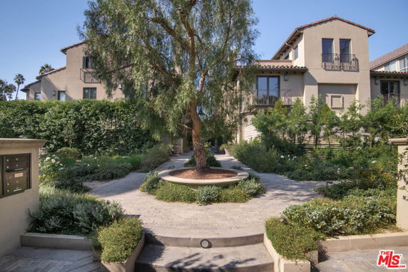 Front view of a two-story house with multiple balconies and a landscaped garden.