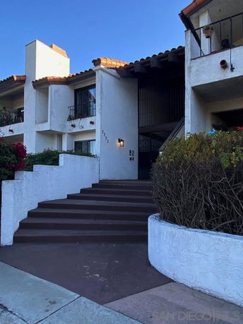 Front view of a multi-story building with a staircase leading to the entrance.