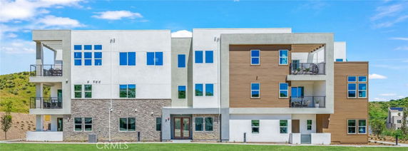 Front view of a modern multi-story building with balconies and large windows.