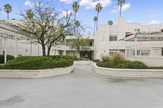 Front view of a modern residential building with white walls and a courtyard.