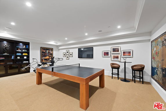 Room with a ping pong table, decorated walls, and seating area.