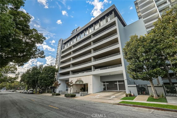 Front view of a multi-story building with balconies and a garage entrance.