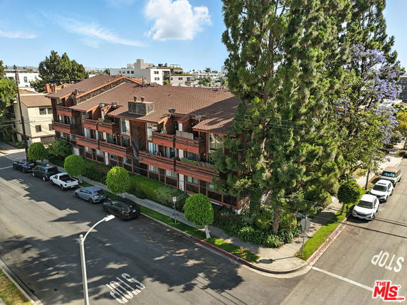 Aerial view of a multi-story residential building with a red tile roof and balconies.