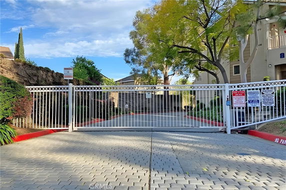 Front view of a gated residential complex with a paved driveway.