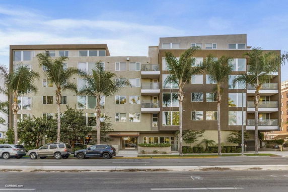 Front view of a multi-story apartment building with balconies and large windows.
