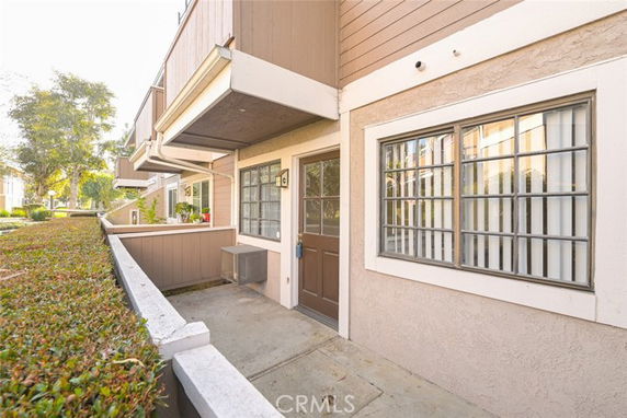Front view of a residential building with a small patio and windows.