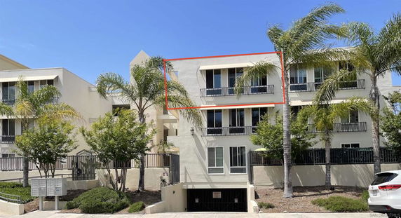 Front view of a multi-story residential building with balconies and palm trees.