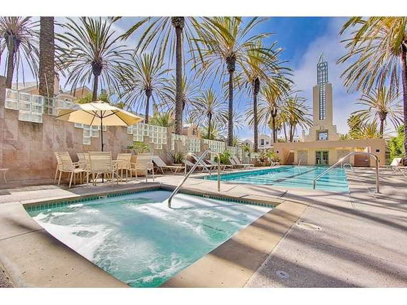 Outdoor area featuring a swimming pool and hot tub surrounded by palm trees.