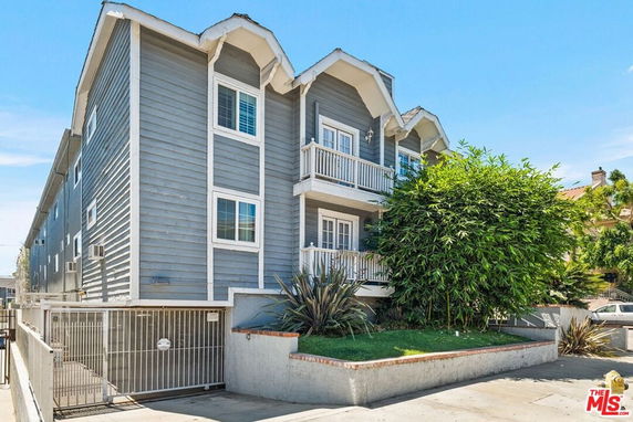 Front view of a multi-story residential building with balconies and gated parking.