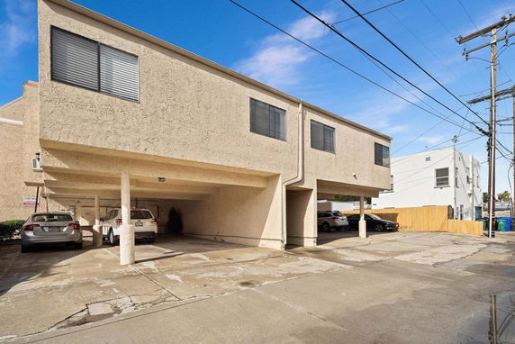 Open parking area beneath a two-story building.