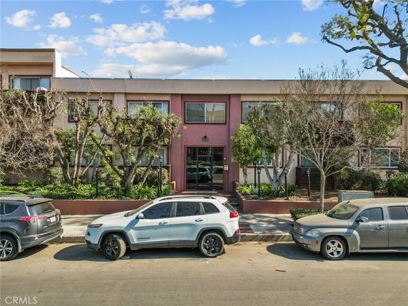 Front view of a two-story building with a central entrance and surrounding greenery.