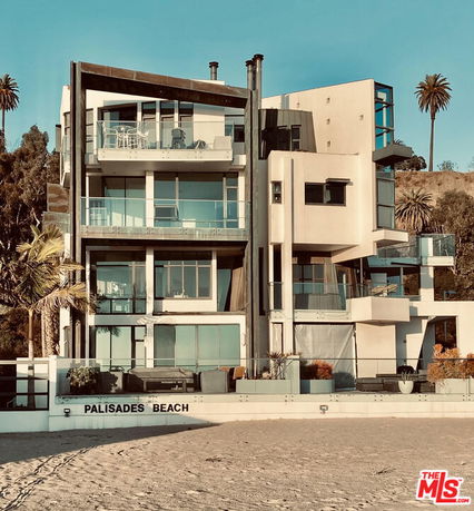 Front view of a multi-story modern beach house with large windows and balconies.