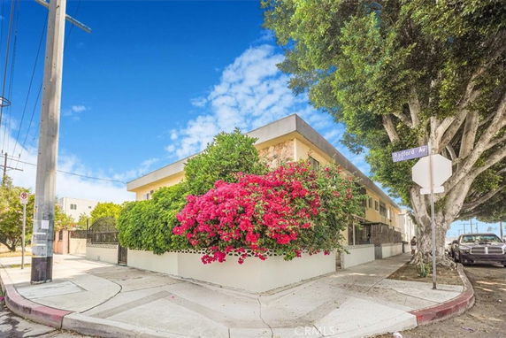 Front view of a two-story building on a street corner with lush greenery and flowering plants.