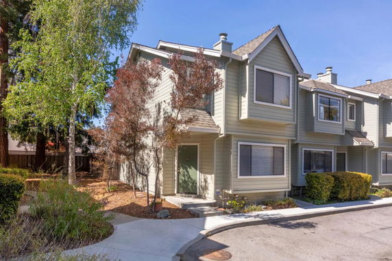 Front view of a two-story townhouse with green exterior and large windows.