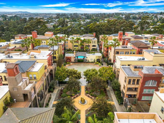 Aerial view of a complex of colorful multi-story buildings with greenery in the center court.