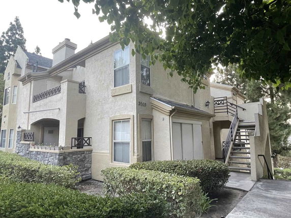 Front view of a two-story building with balconies and exterior stairs.