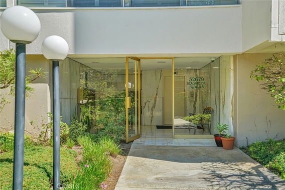 Front view of a building entrance with glass doors and surrounding greenery.