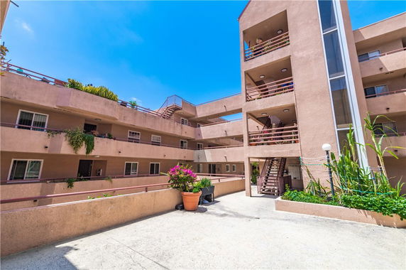 View of a multi-story residential building with balconies and potted plants.