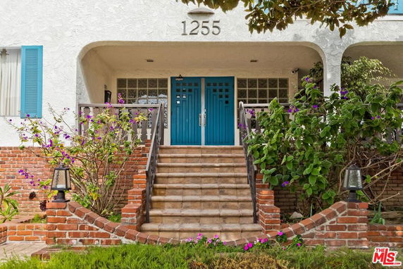 Front view of a house with a staircase leading to a blue front door.