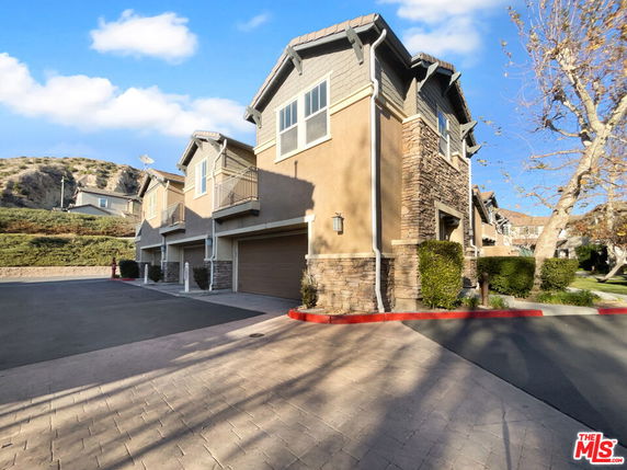 Front view of a multi-story house with stone accents and garage entry.