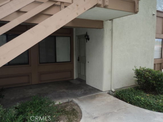 Front view of a building entrance with a staircase above and a door leading inside.
