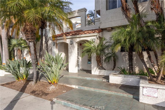 Front view of a multi-story building with a tiled entrance and palm trees.