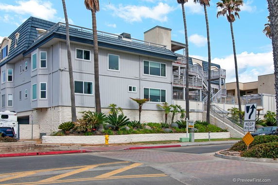 Front view of a multi-story building with a modern exterior and a landscaped front yard.