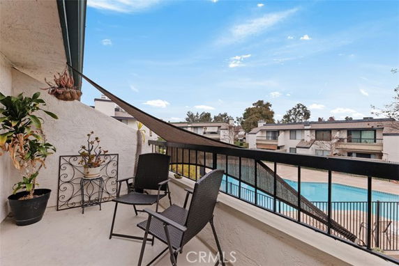 View from a balcony overlooking a swimming pool and surrounding buildings.