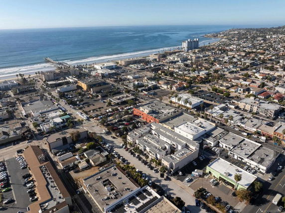 Aerial panoramic view of a coastal city area with buildings and ocean in the background.