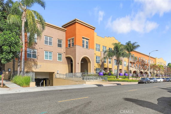 Front view of a colorful multi-story building with arches and a parking entrance.