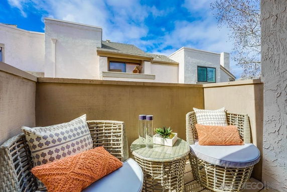 Balcony view showing adjacent buildings with stucco walls and sloped roofs.