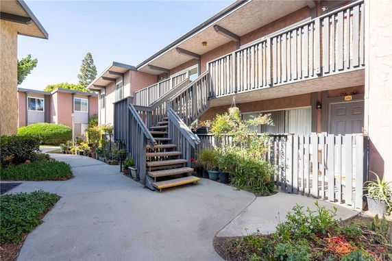 Front view of a two-story building with an external staircase and balcony.