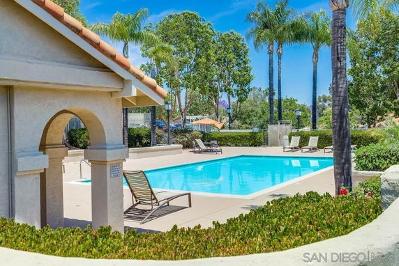 Outdoor swimming pool area with lounge chairs and surrounding greenery.