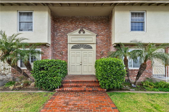 Front view of a two-story house with a brick entryway and central door.