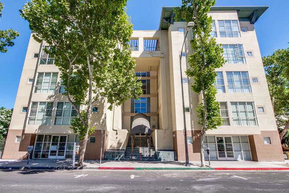 Front view of a multi-story apartment building with large windows and a central entrance staircase.
