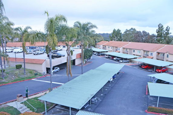 View of a residential parking area with covered parking spaces and adjacent buildings.