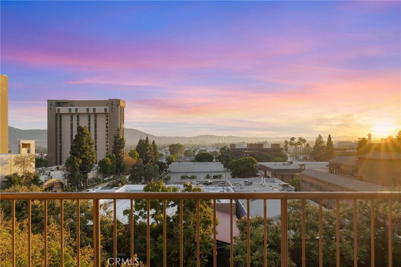 Panoramic view from a balcony overlooking city buildings at sunset.