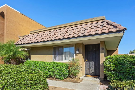 Front view of a small house with a tiled roof and front door.
