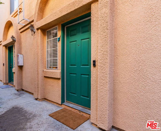 Exterior view of a building entrance with green doors and textured walls.
