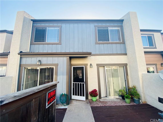 Front view of a two-story house with a central entrance and sliding glass doors.